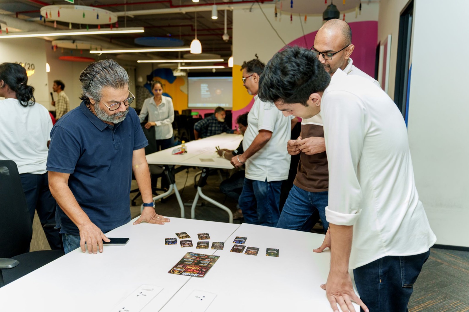 Participants standing around a table studying their Brand Premier League capability-card draft
